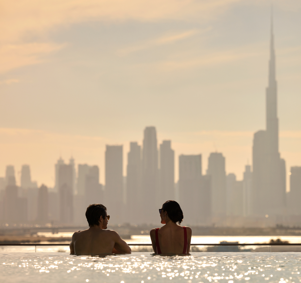 Couple enjoying honeymoon by one of the infinity pool at an Address Hotel during sunset hour overlooking Dubai Skyline views